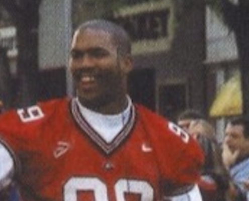 football player waves to fans during parade